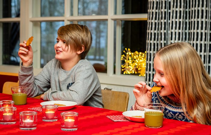 Kaksi lasta syö piparia jouluisessa ruokapöydässä.