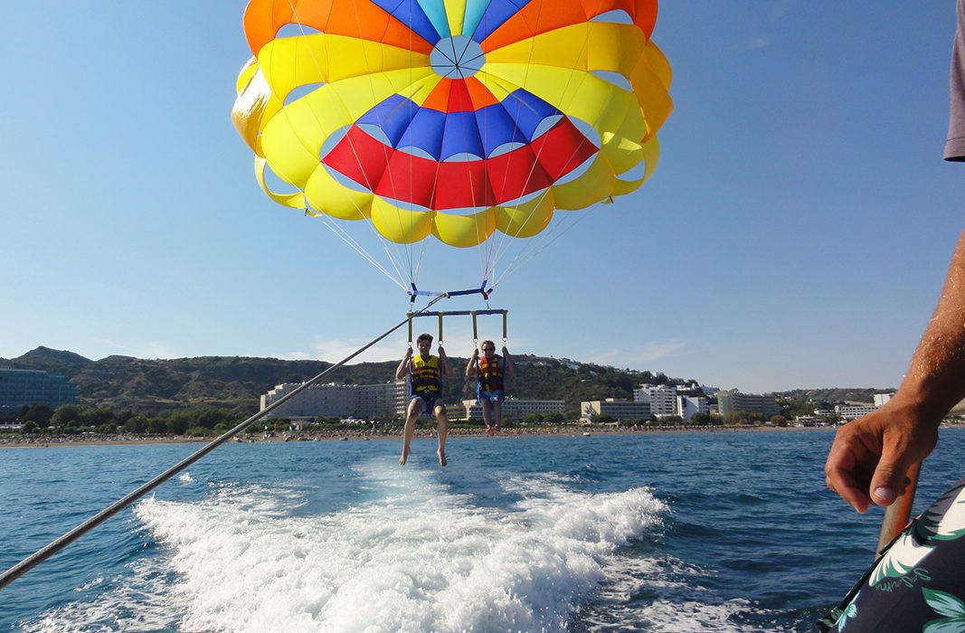 Two people parachuting over the water.