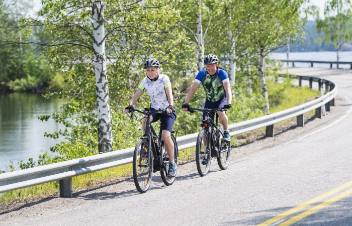 Kaksi pyöräilijää järvimaisemassa.