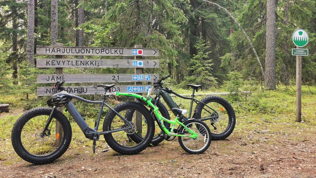 Maastopyörät reittiopasteen edessä metsämaisemassa.