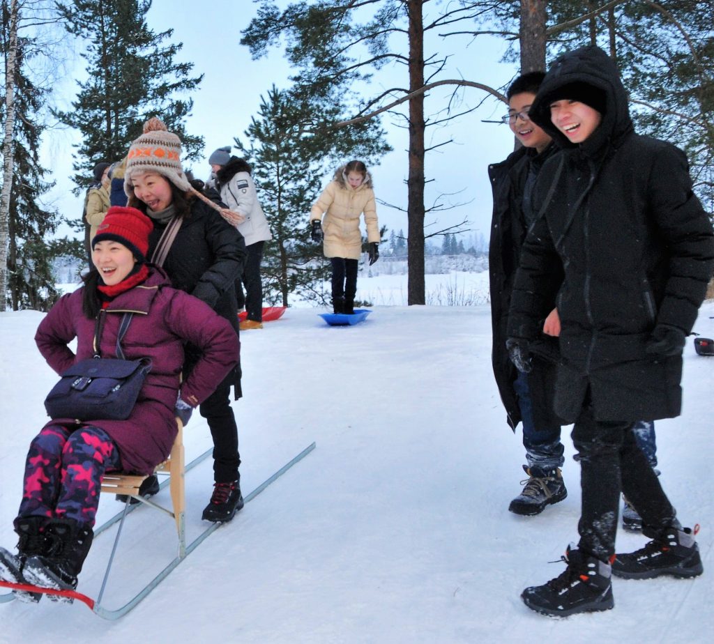 kaksi naista laskee potkukelkalla mäkeä.