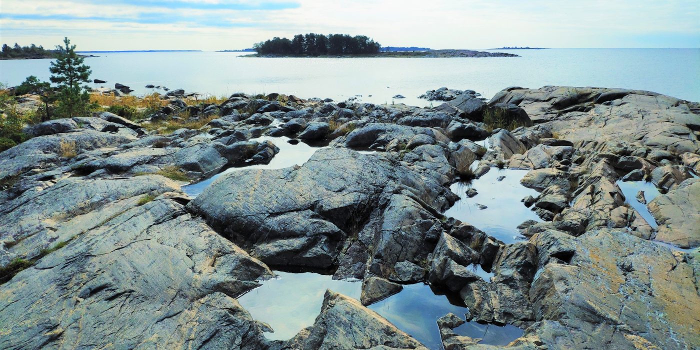 Kehitetään Kansainvälinen Opetussuunnitelma3 Kuvituskuvaa jossa kallioinen rantamaisema.