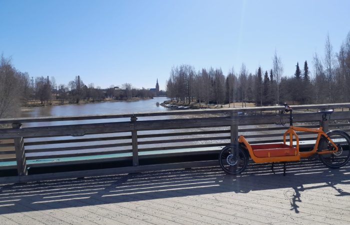 Pyörä kävelysillalla. Taustalla näkyy joki.