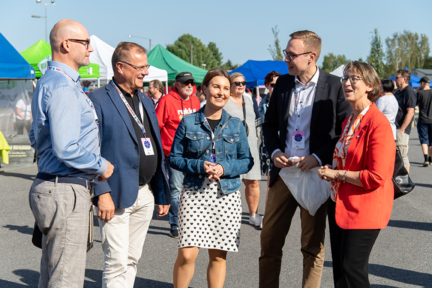 Lähiruokapäivä2023 Kuva ElmeriElo (82) Web Petri Huru , Matias Marttinen, Eeva Kalli ja Juha Viitala seisovat keskellä markkinahumua hymyssäsuin.