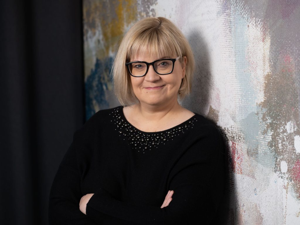 Kuvassa Sanna-Mari Renfors poseeraa hymyillen kädet puuskassa.