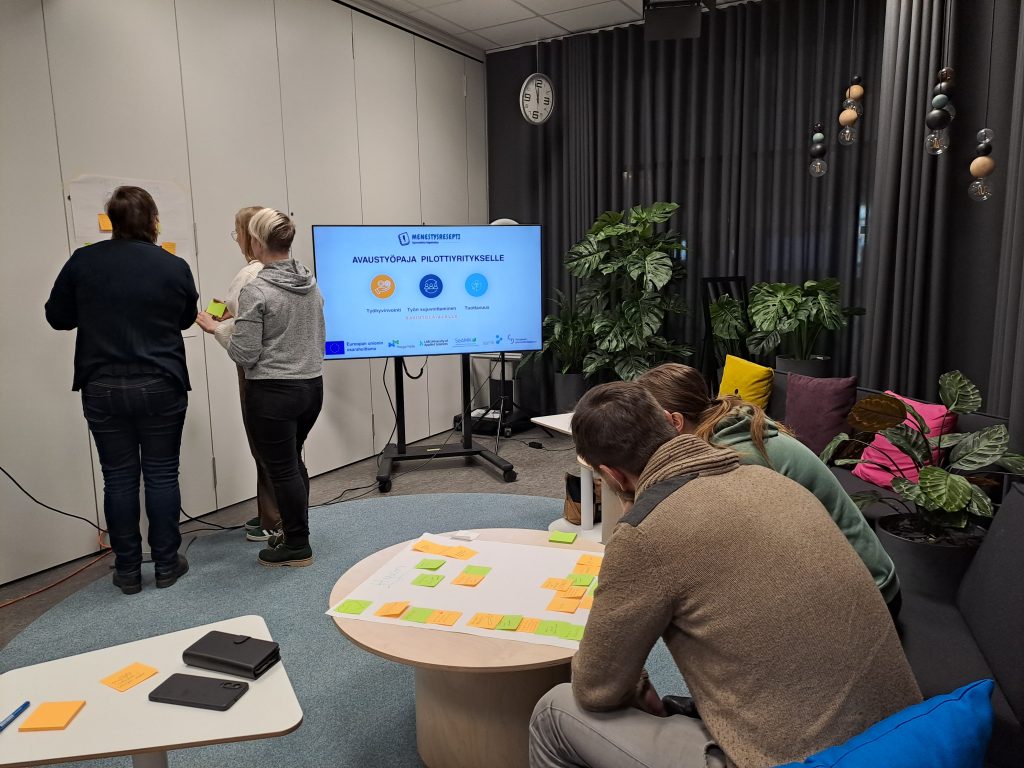 Huoneessa ihmisiä keskustelemassa.