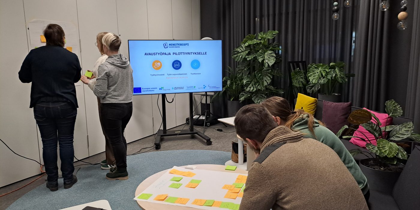 Huoneessa ihmisiä keskustelemassa.