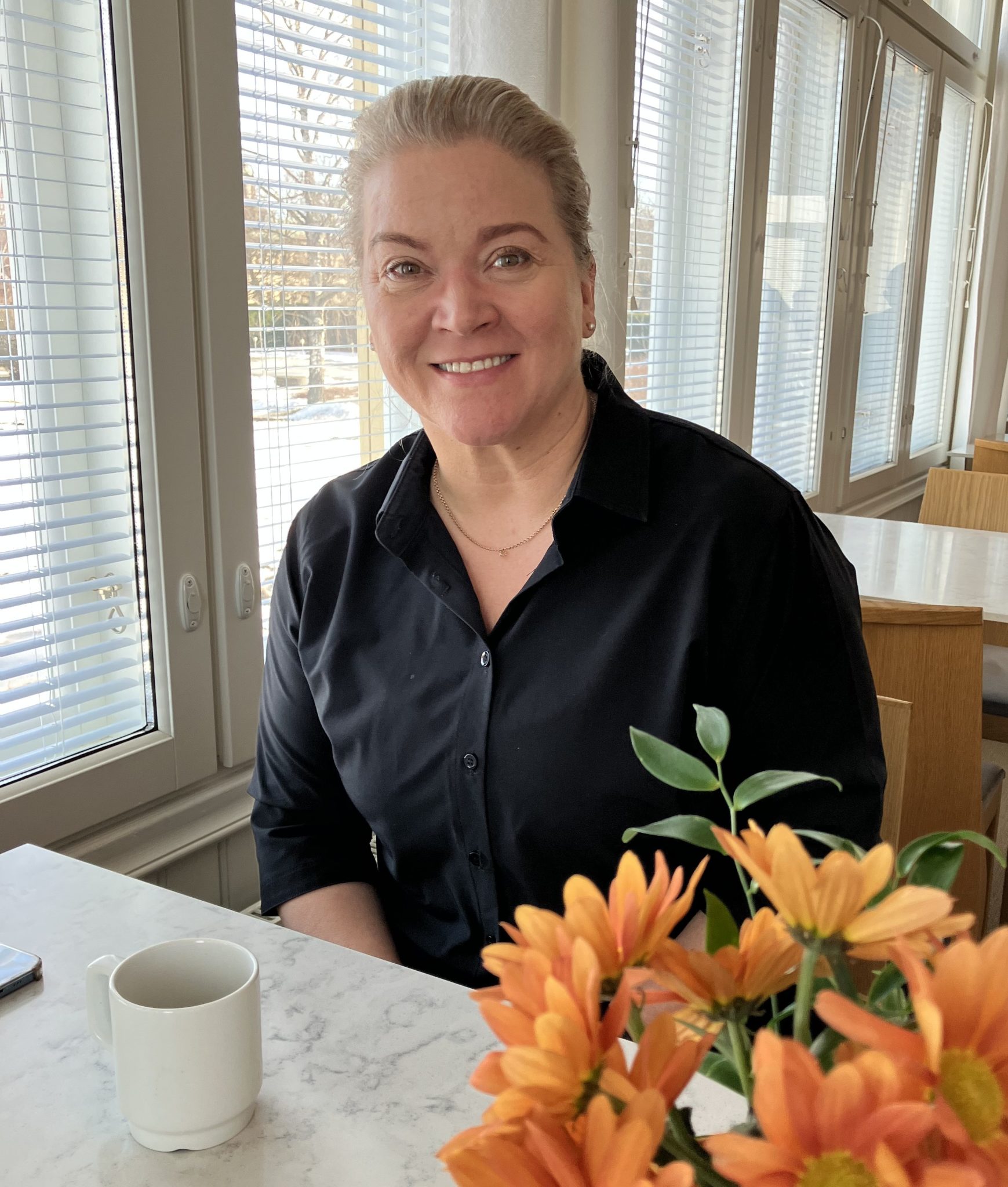 Milla Laurila istuu kahvikupin ääressä Ahlstöm Ruukin pöydän vieressä.