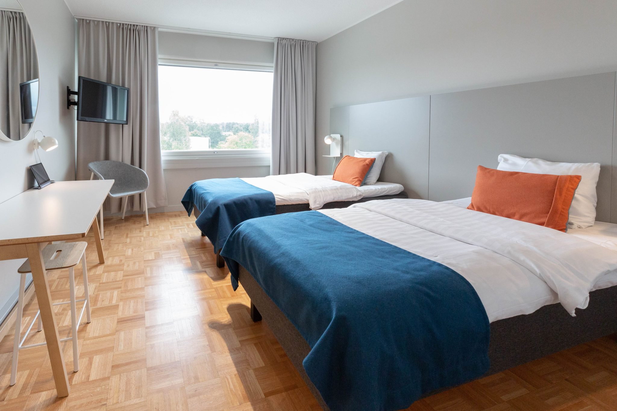 Kahden hengen hotellihuone, kaksi sänkyä, työpöytä ja ikkuna.