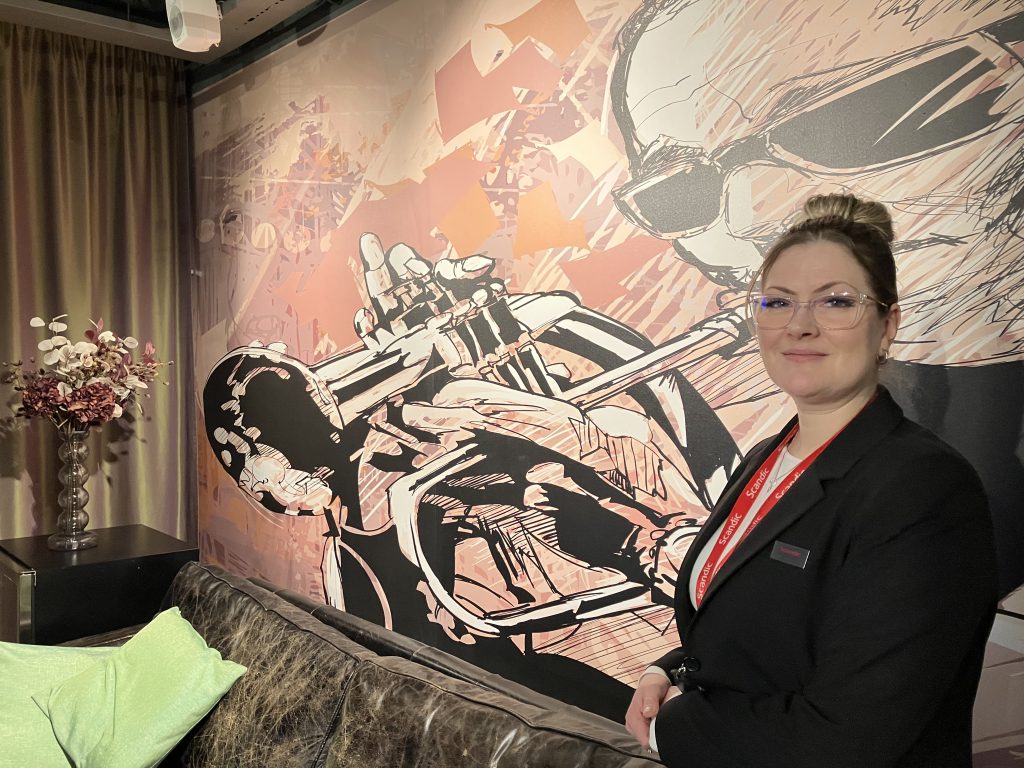 Hotellin oleskelutila, henkilö seisoo suuren seinämaalauksen edessä.