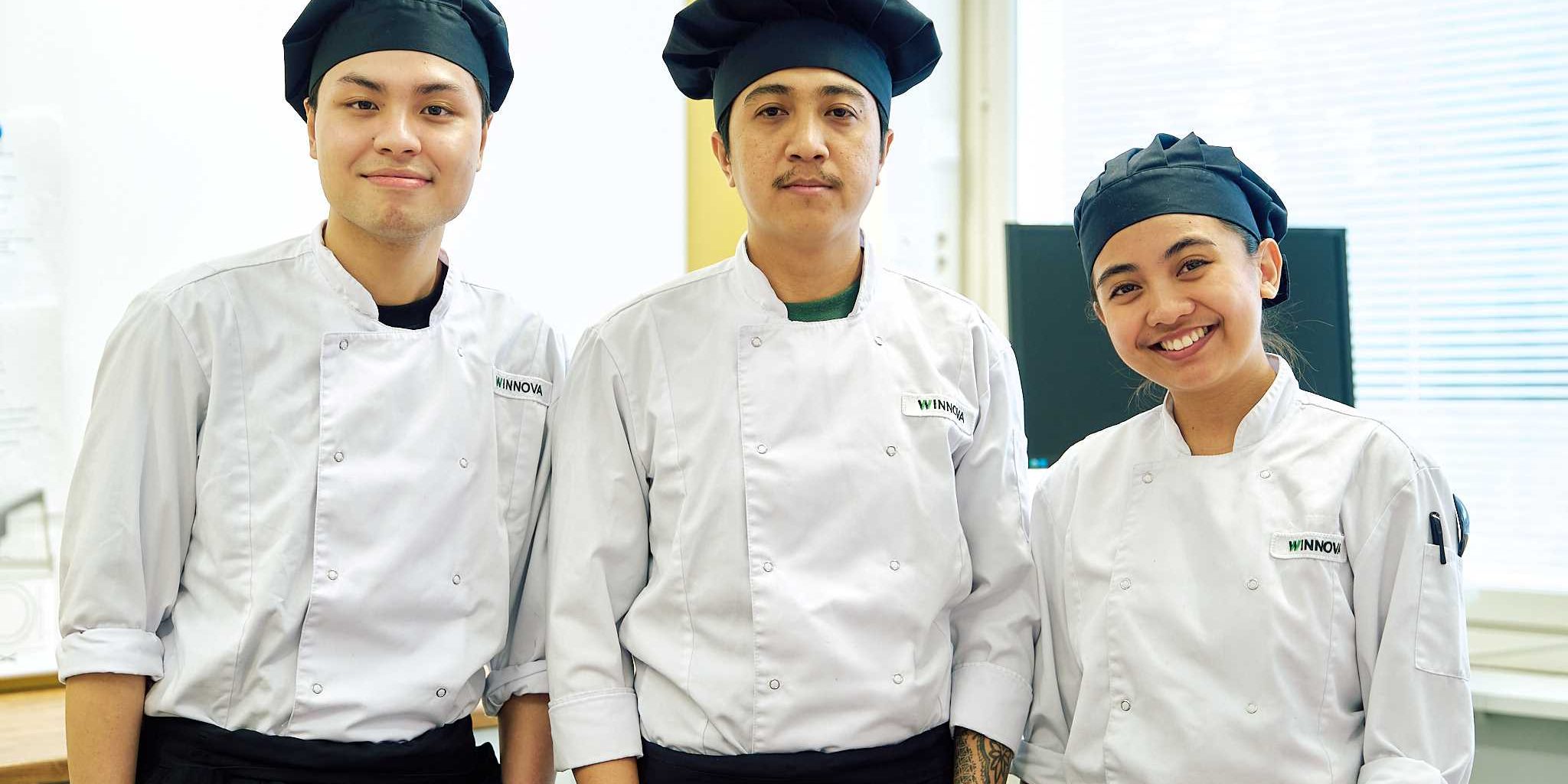 DSC04558 Three young people standing side by side, dressed in chef uniforms.