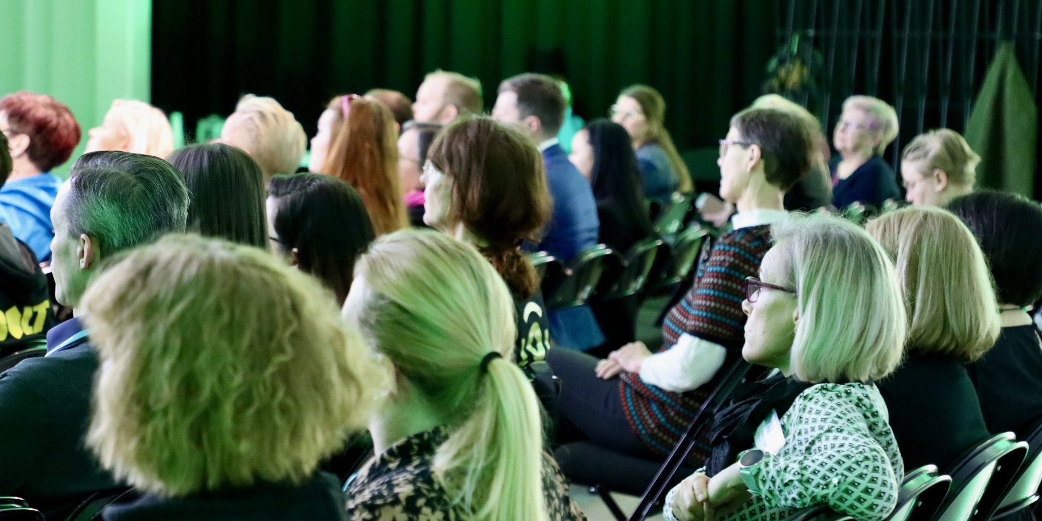 Close-up of a lecture at the fair. People sitting in rows of benches listening to the presentation.