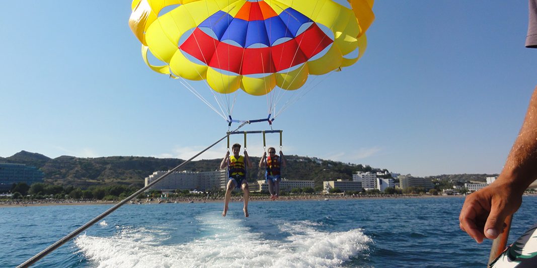 Two people parachuting over the water.